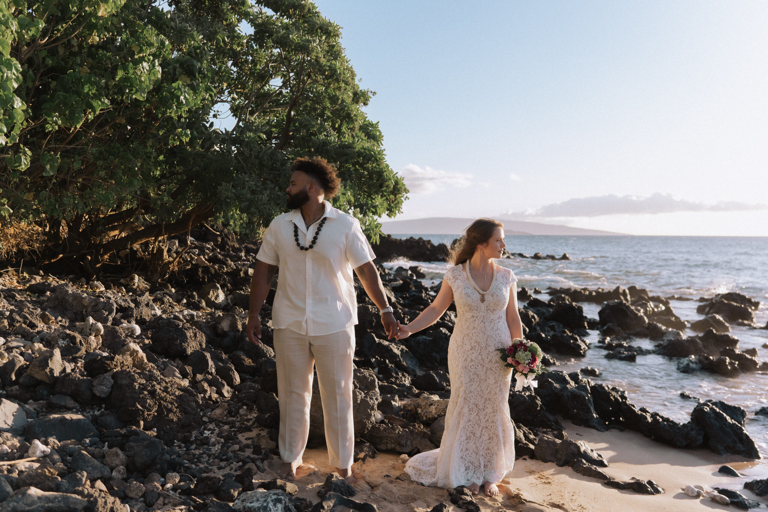 Layn and Dylan walking along the rocky Maui coastline after their Maluaka Beach elopement.
